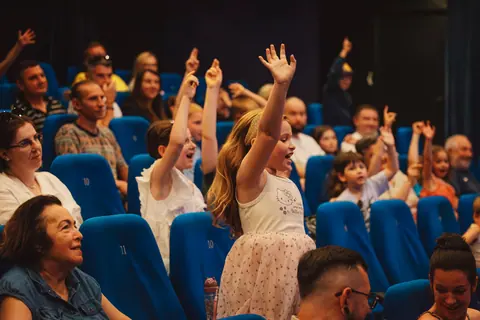 Dzieci na widowni podnoszą ręce podczas spektaklu dla dzieci w Warszawie